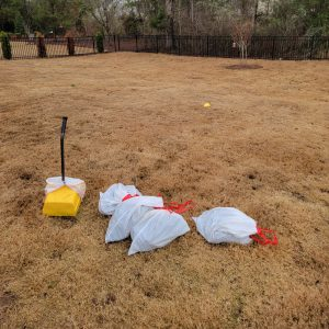 pooper scooper service bags piled up next to tools in recently cleaned yard.